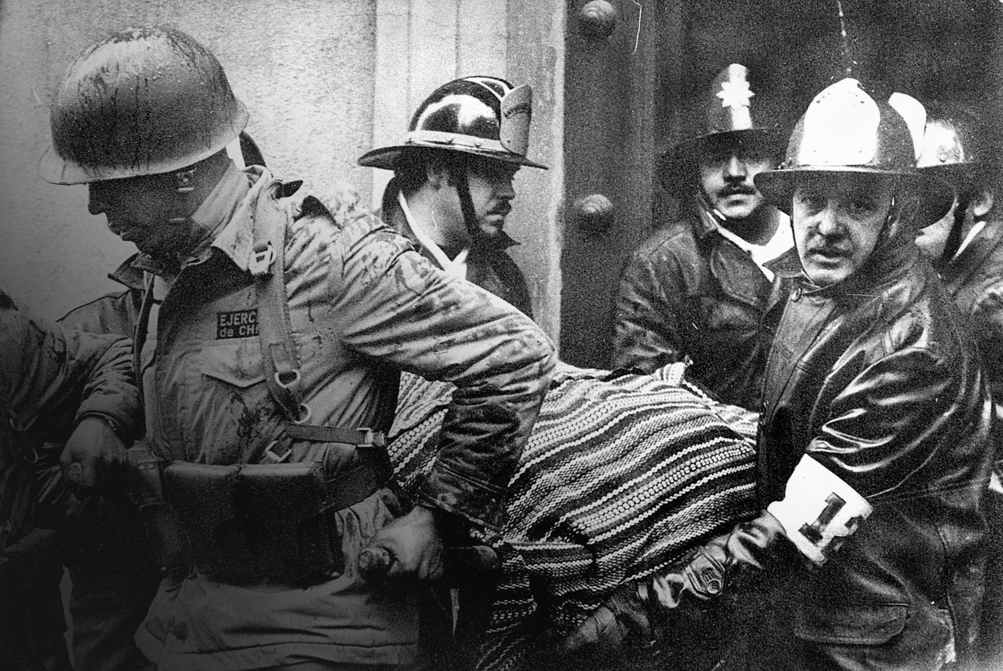 Soldados y&nbsp;bomberos sacan el&nbsp;cuerpo del presidente Salvador Allende, envuelto en&nbsp;un&nbsp;poncho boliviano, del destruido Palacio de&nbsp;La&nbsp;Moneda.